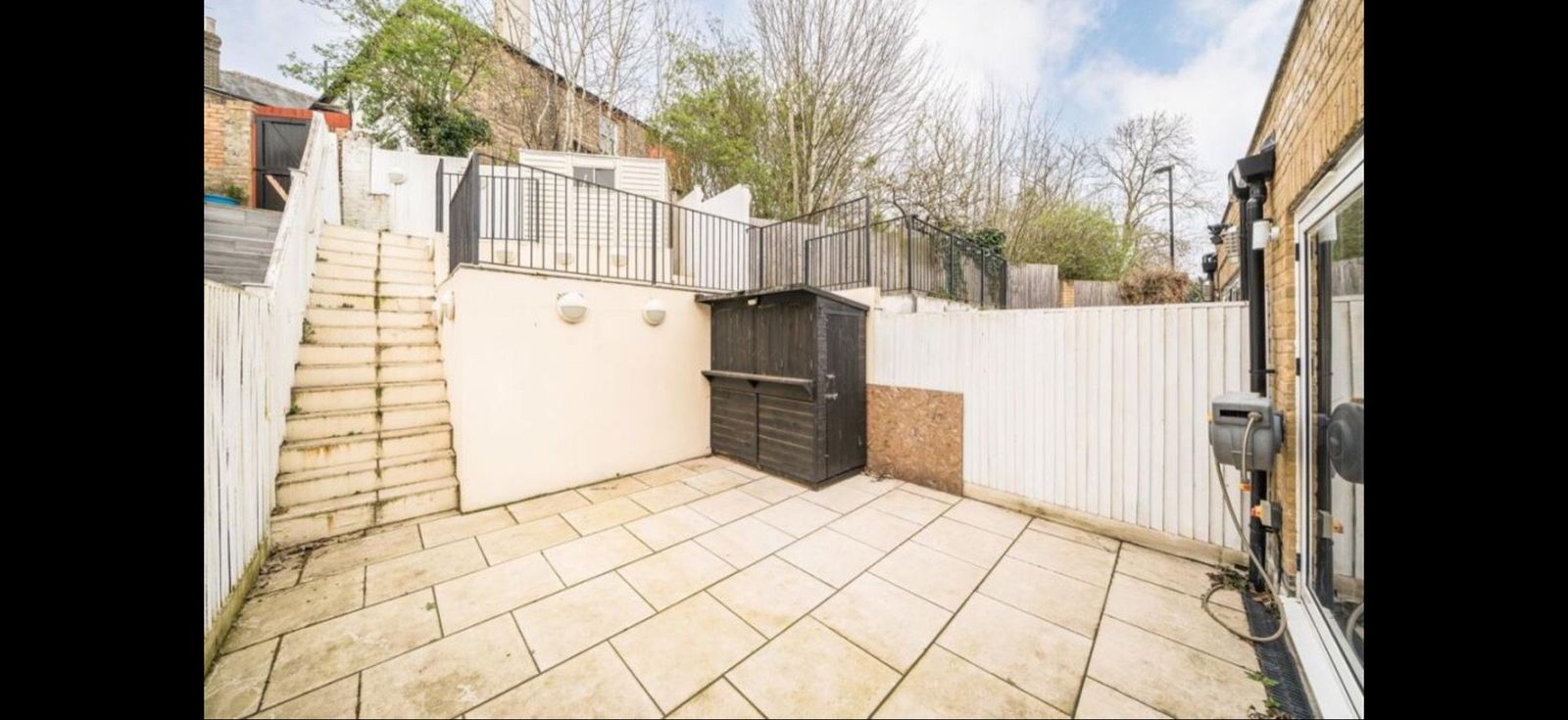 Private rear courtyard with stone paving and steps up to the upper level