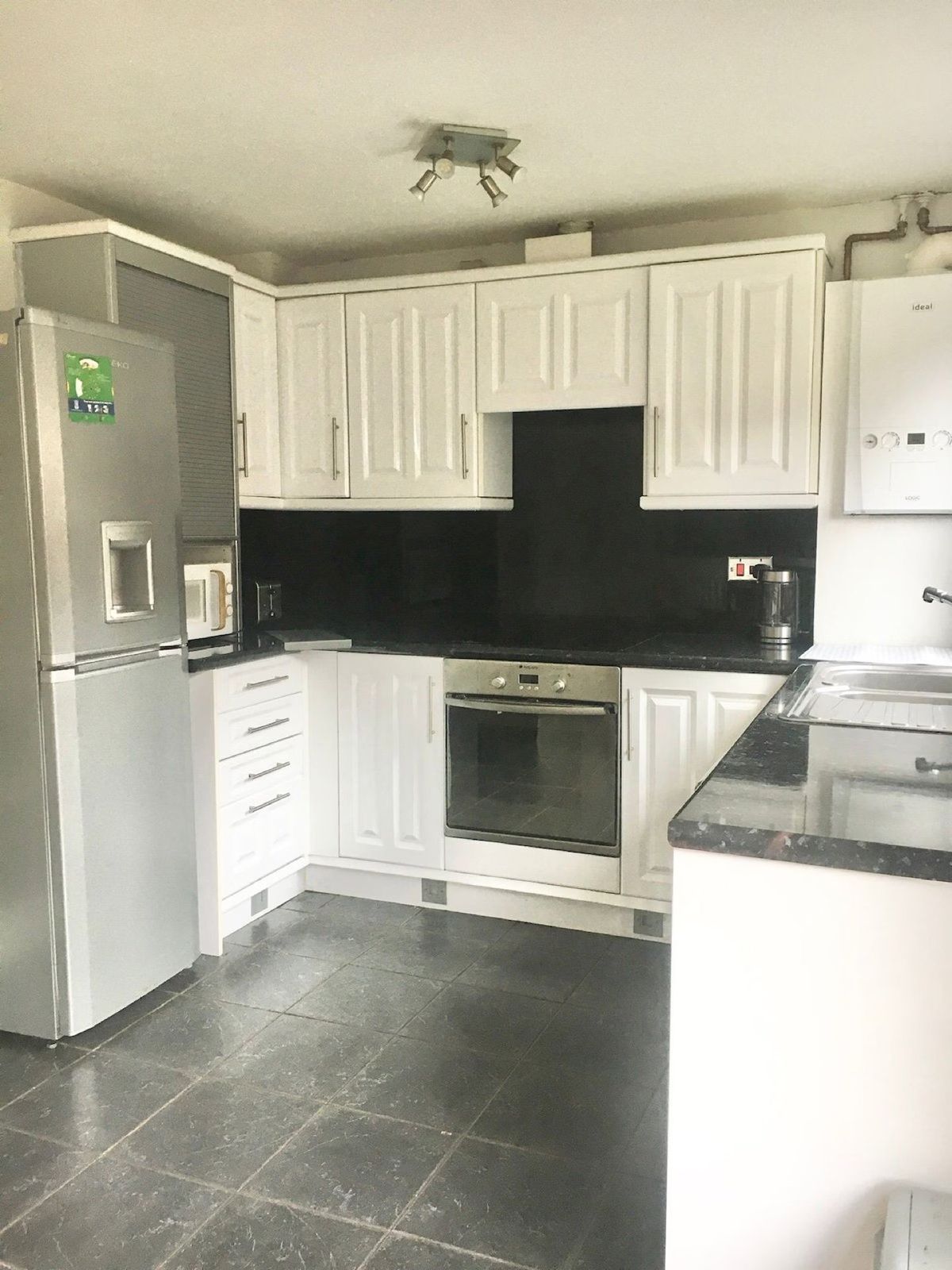 Kitchen-diner — white cabinets, oven, fridge-freezer, dark countertops, dark tile floor