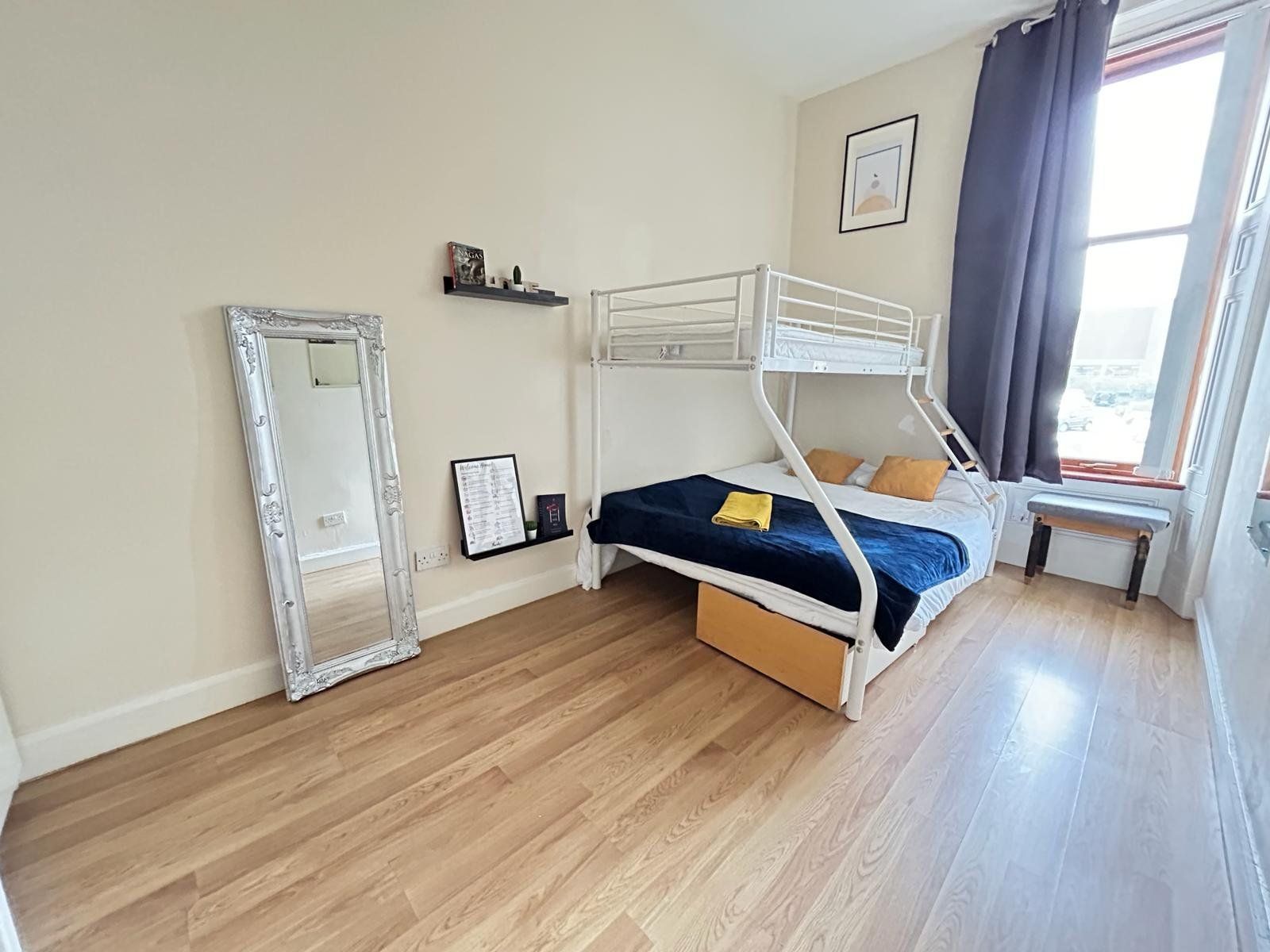 Bunk bedroom — triple bunk bed with king at the bottom and single on top, ornate silver mirror, daytime light